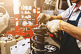 Mechanic checking a car's shock absorbers in a workshop.
