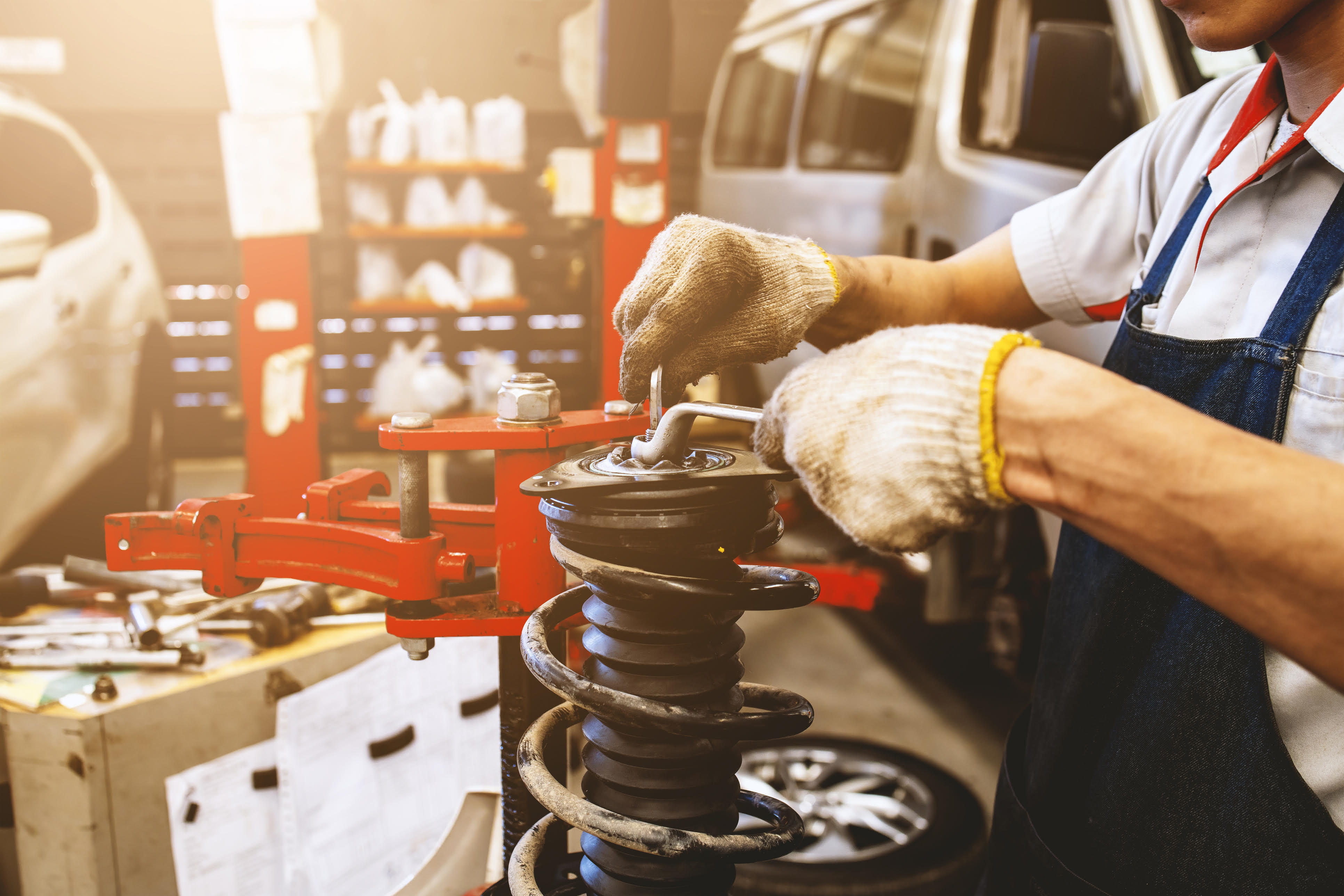 Mechanic checking a car's shock absorbers in a workshop.