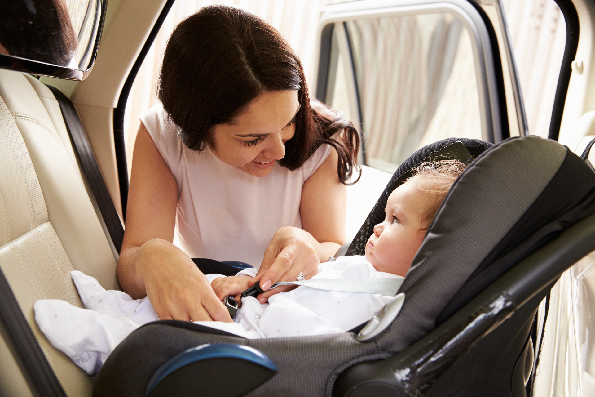 Child safely secured in a child car seat in the back seat of a car.